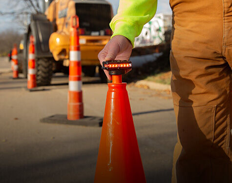 person placing a guardian angel device on top of a traffic cone