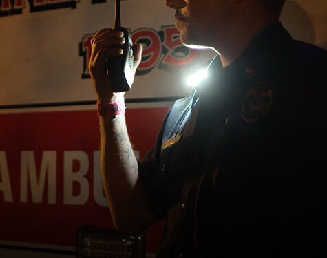 person in uniform standing next to an abulance wearing a guardian angel safety light