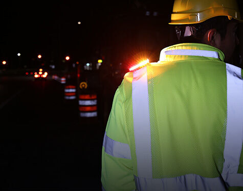 person in reflective vest and a hardhat wearing a guardian angel safety light