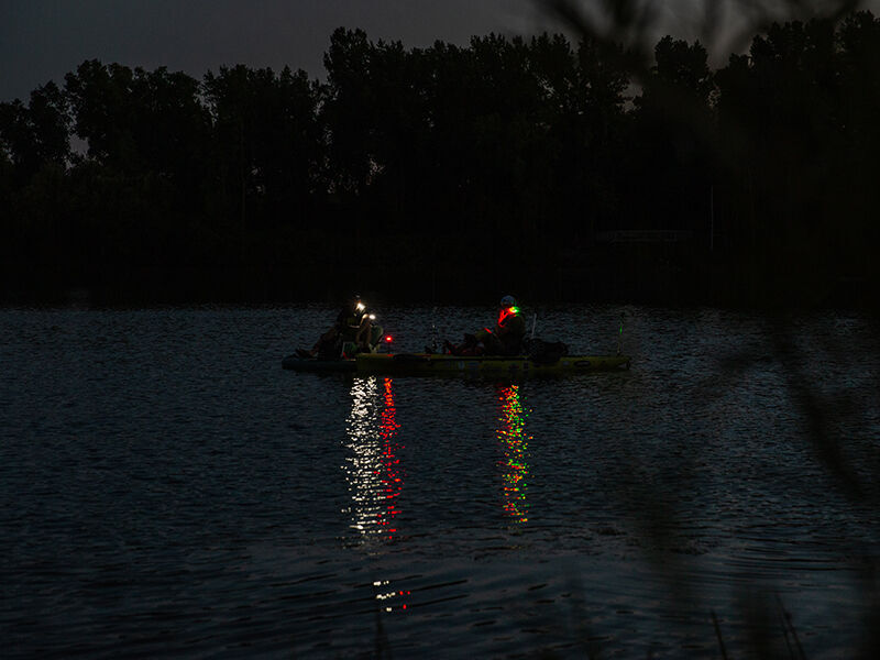 people in a boat on water in the distance with guardian angel lights shining