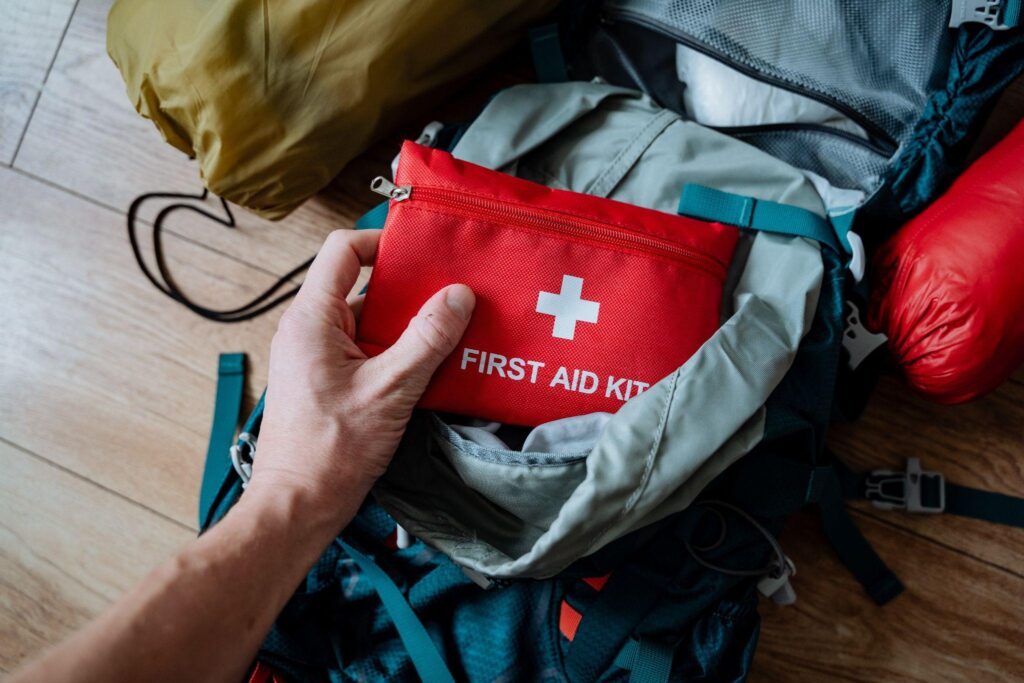 a single individual is carefully placing a first aid kit into a backpack